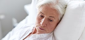 Disabled Elderly woman praying while sitting at home with wheelchair in the background